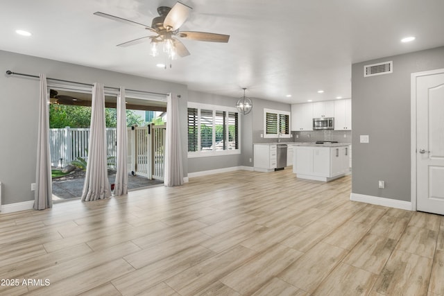 unfurnished living room featuring a ceiling fan, baseboards, light wood finished floors, recessed lighting, and a chandelier