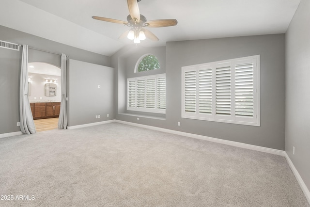 unfurnished bedroom with carpet, ensuite bath, baseboards, ceiling fan, and lofted ceiling