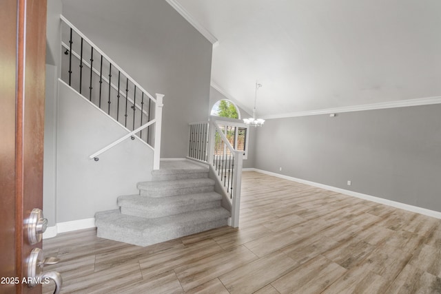 stairs with a chandelier, ornamental molding, baseboards, wood finished floors, and high vaulted ceiling
