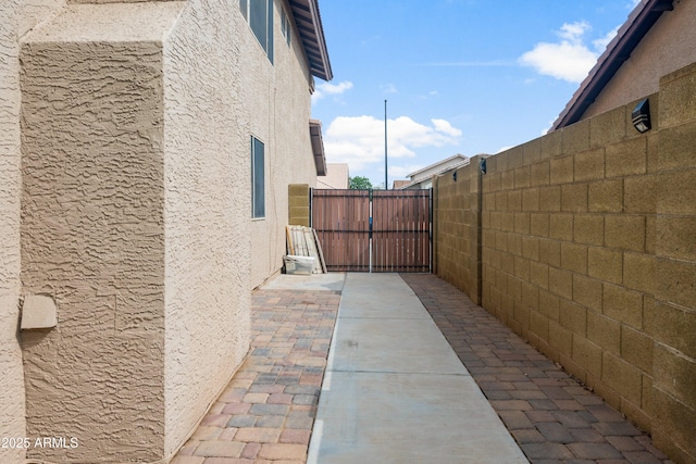 view of property exterior with stucco siding, a gate, and fence