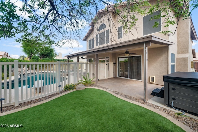 rear view of property featuring stucco siding, ceiling fan, a patio, and a hot tub