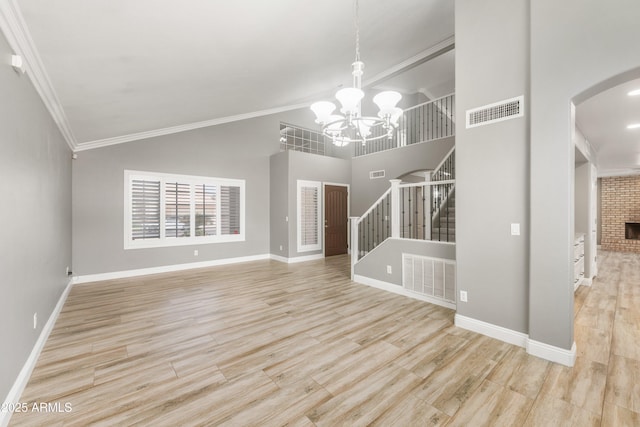 unfurnished living room with stairs, a chandelier, ornamental molding, arched walkways, and wood finished floors