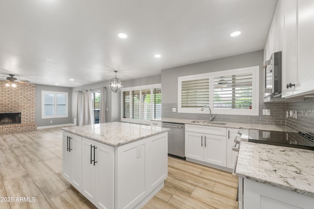 kitchen with stainless steel appliances, a sink, a center island, open floor plan, and a ceiling fan