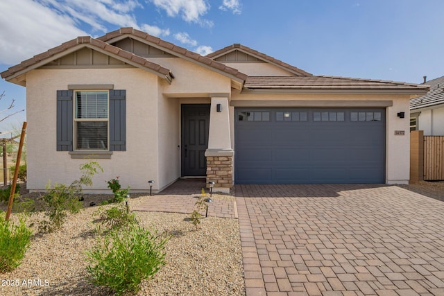 ranch-style home featuring an attached garage, a tiled roof, decorative driveway, and stucco siding