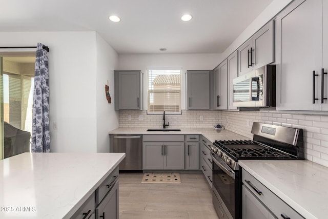 kitchen with appliances with stainless steel finishes, gray cabinets, and a sink