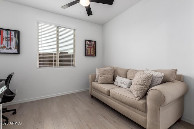 living area featuring light wood-type flooring, baseboards, and a ceiling fan