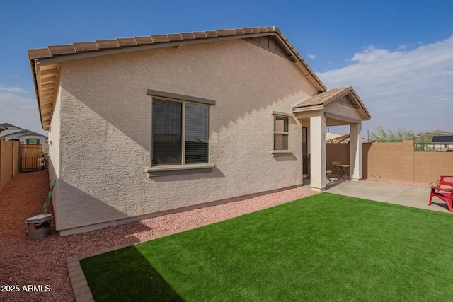 rear view of house with a patio, a fenced backyard, a tiled roof, a lawn, and stucco siding