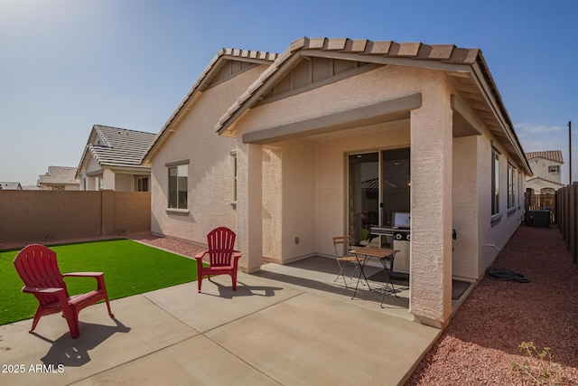 rear view of house featuring a patio, a yard, a fenced backyard, and stucco siding