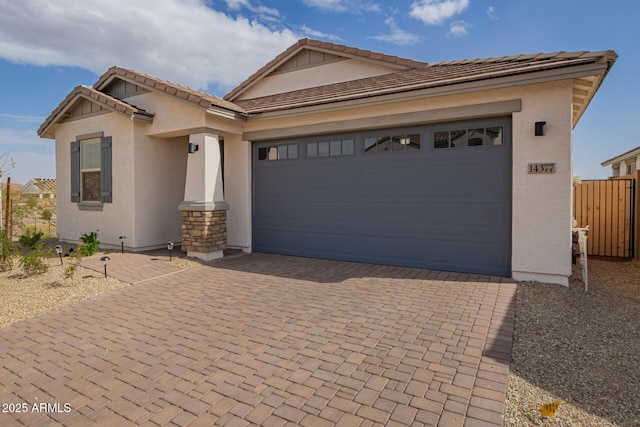 view of front of house featuring decorative driveway, fence, an attached garage, and stucco siding