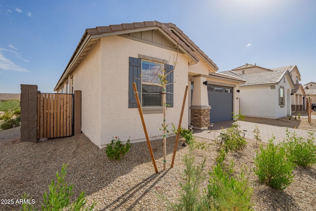 view of front facade featuring an attached garage, driveway, a tiled roof, and stucco siding