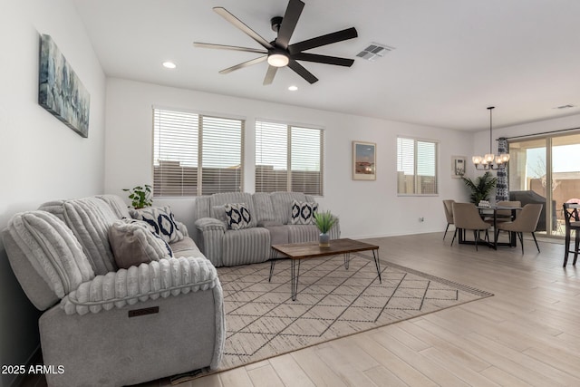 living area with recessed lighting, ceiling fan with notable chandelier, visible vents, baseboards, and light wood-style floors