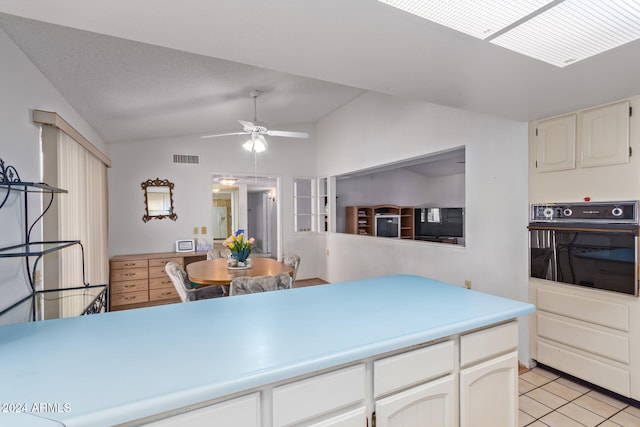 kitchen featuring ceiling fan, light tile patterned floors, oven, and vaulted ceiling