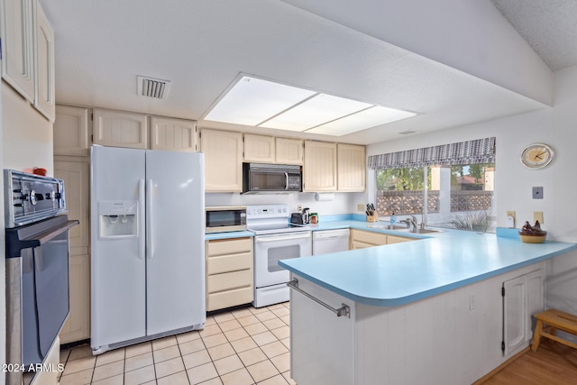 kitchen featuring kitchen peninsula, sink, black appliances, light tile patterned floors, and lofted ceiling