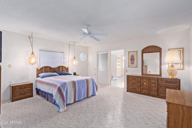 bedroom featuring light carpet, a textured ceiling, ensuite bath, and ceiling fan