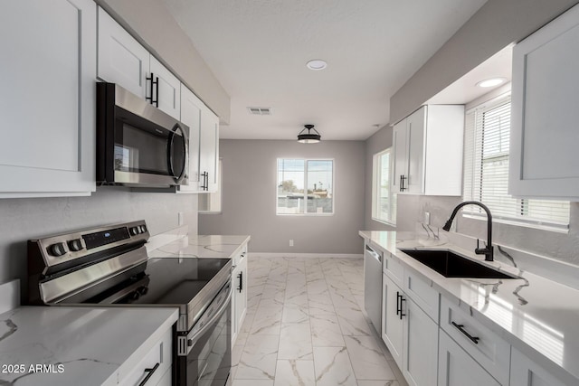 9105 N 13th St, Phoenix, AZ 85020 - kitchen featuring marble finish floor, a sink, white cabinetry, appliances with stainless steel finishes, and baseboards