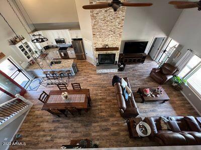 living room featuring ceiling fan, a towering ceiling, and a stone fireplace