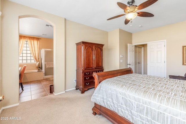 bedroom with ceiling fan, light carpet, and ensuite bath