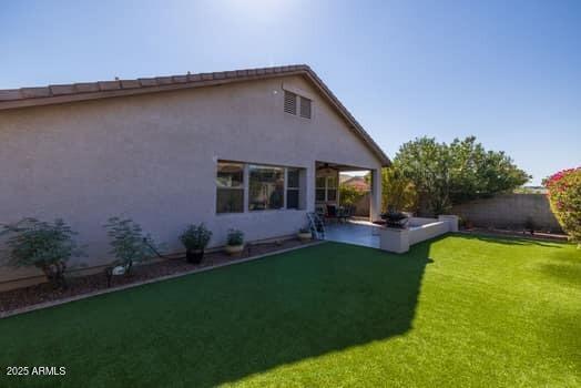 back of house with a patio and a lawn