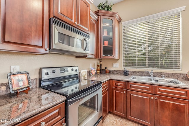 kitchen with sink, light tile patterned flooring, light stone countertops, and appliances with stainless steel finishes