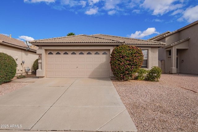 view of front facade with a tiled roof, an attached garage, driveway, and stucco siding