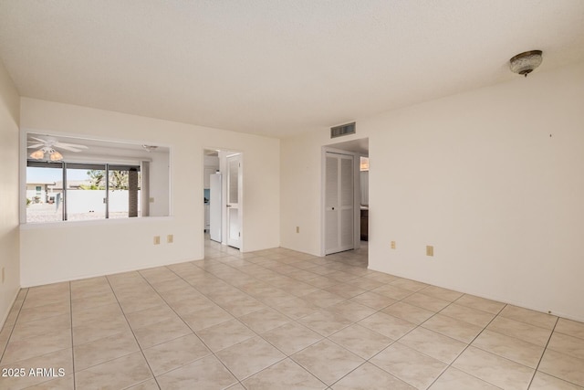 empty room with ceiling fan, visible vents, and light tile patterned flooring