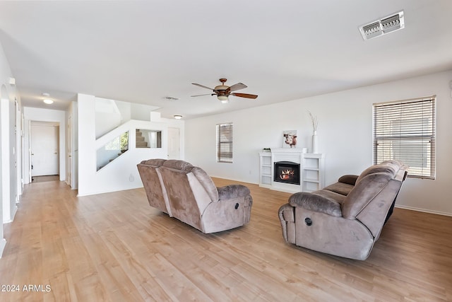 living area with light wood-style flooring, visible vents, and a glass covered fireplace