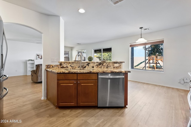 kitchen with stainless steel appliances, light wood finished floors, a sink, and light stone countertops