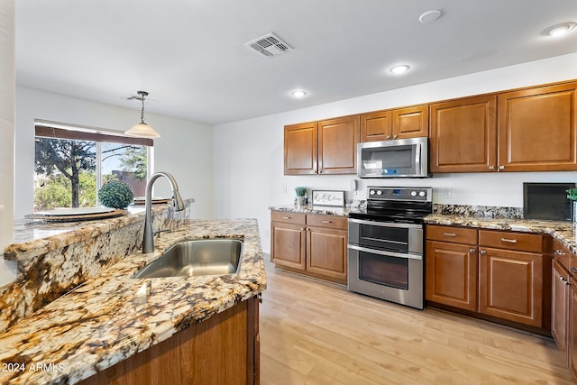 kitchen featuring appliances with stainless steel finishes, a sink, visible vents, and light stone countertops