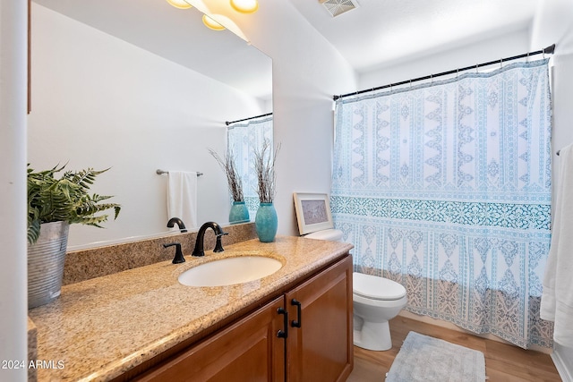 bathroom with curtained shower, toilet, wood finished floors, vanity, and visible vents