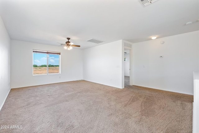 carpeted spare room featuring ceiling fan, visible vents, and baseboards