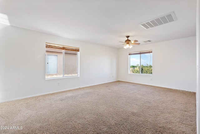 carpeted empty room featuring ceiling fan, visible vents, and baseboards