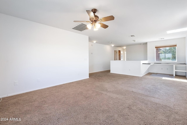 empty room with a ceiling fan, light colored carpet, visible vents, and baseboards