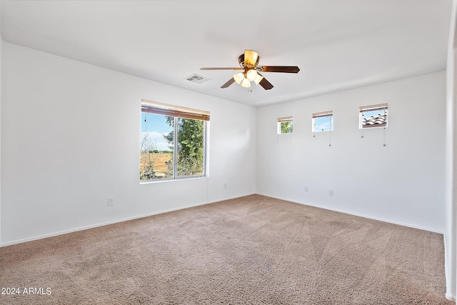 carpeted spare room with baseboards, visible vents, and a ceiling fan