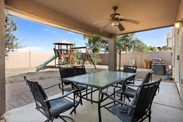 view of patio featuring outdoor dining area, a playground, a fenced backyard, and cooling unit