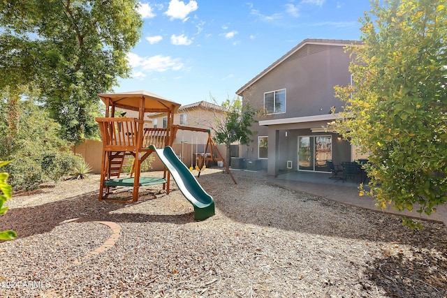 view of playground with fence, central AC unit, and a patio