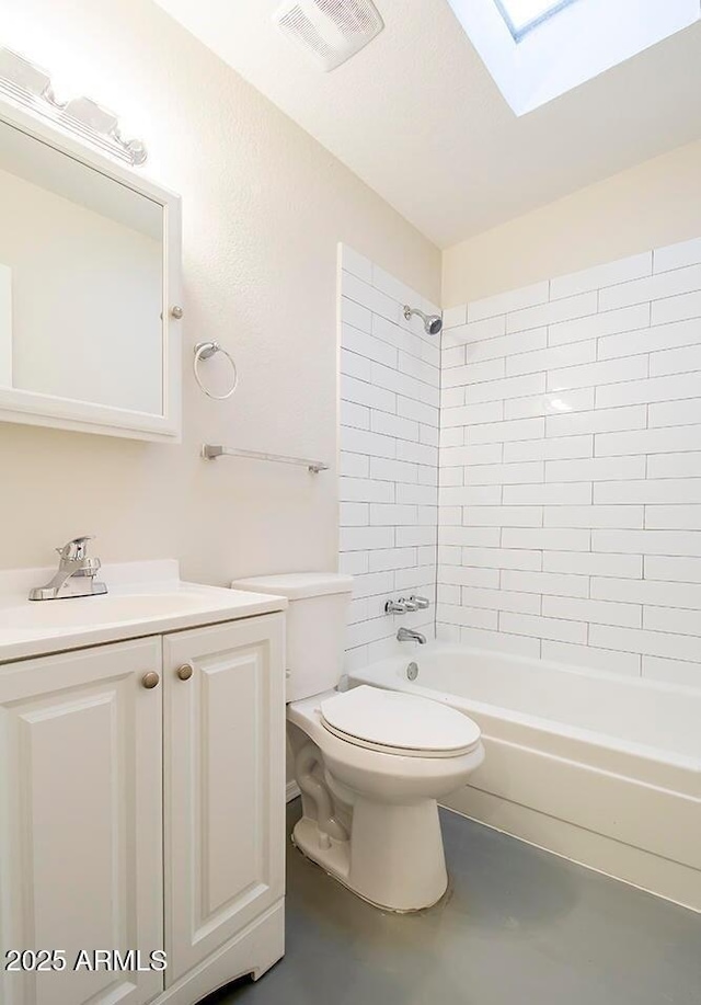 full bathroom featuring toilet, a skylight, tiled shower / bath combo, and vanity