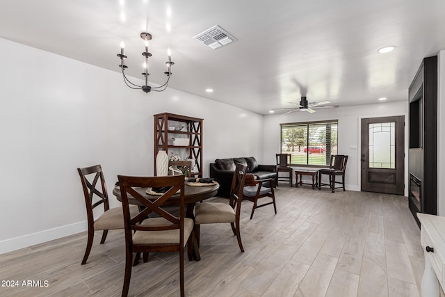 dining space featuring ceiling fan with notable chandelier and light wood-type flooring