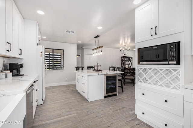 kitchen featuring beverage cooler, black microwave, light wood-type flooring, and decorative light fixtures