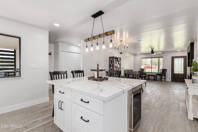 kitchen featuring light wood-type flooring, pendant lighting, light stone counters, and a center island