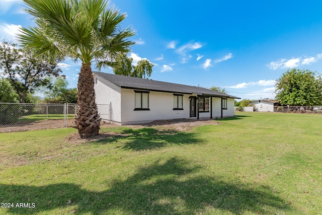 back of house featuring a lawn and a storage shed