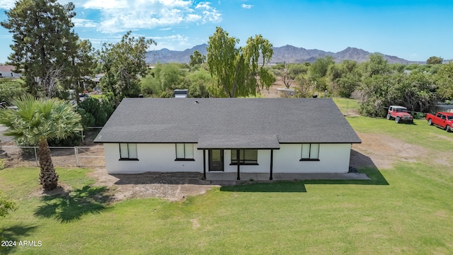 rear view of property featuring a mountain view and a lawn