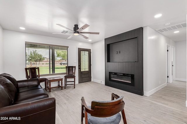 living room featuring a large fireplace, ceiling fan, and light hardwood / wood-style flooring