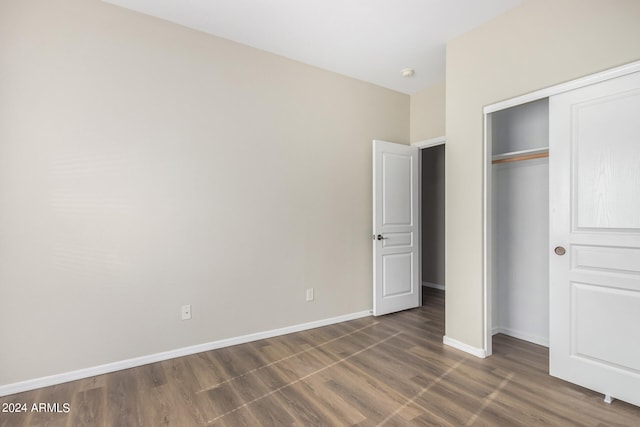 unfurnished bedroom with a closet and dark hardwood / wood-style floors