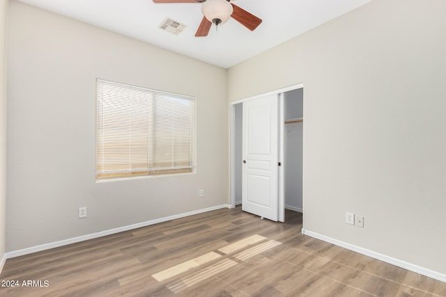 unfurnished bedroom featuring hardwood / wood-style floors, ceiling fan, and a closet