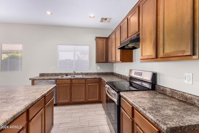 10722 W Jefferson St, Avondale, AZ 85323 - kitchen with stainless steel appliances, under cabinet range hood, a sink, dark countertops, and brown cabinetry
