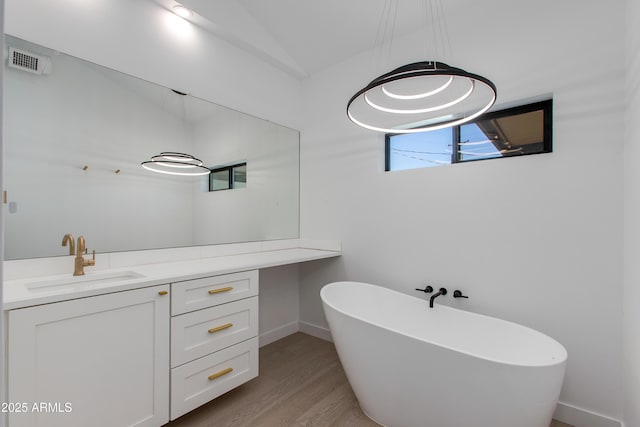 bathroom featuring a freestanding tub, wood finished floors, baseboards, and vanity