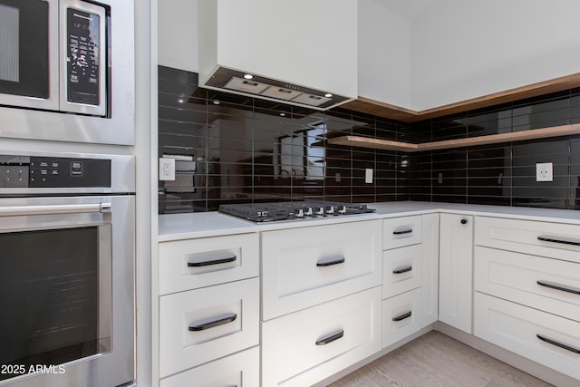 kitchen featuring stainless steel appliances, backsplash, white cabinetry, and light countertops