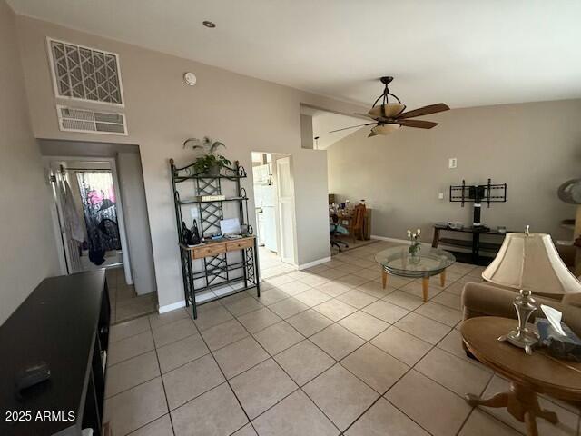 living area featuring light tile patterned floors, baseboards, lofted ceiling, and a ceiling fan