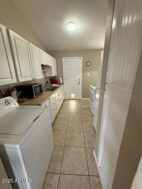 clothes washing area featuring baseboards, light tile patterned floors, laundry area, washer / clothes dryer, and a sink