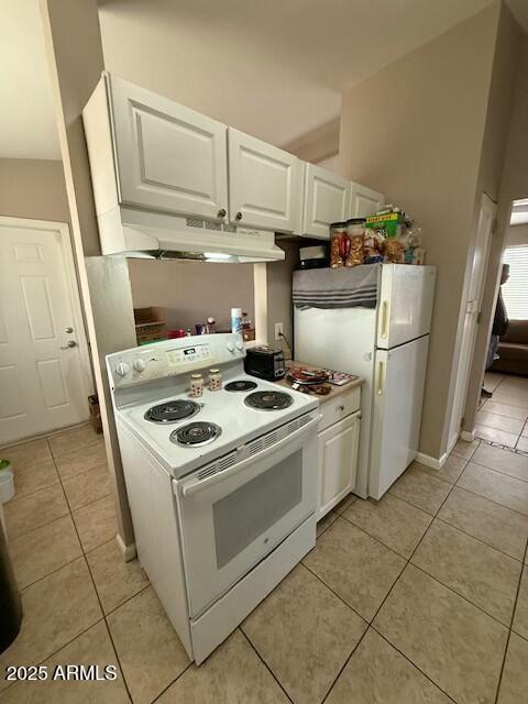 kitchen with under cabinet range hood, white appliances, white cabinets, and light tile patterned flooring